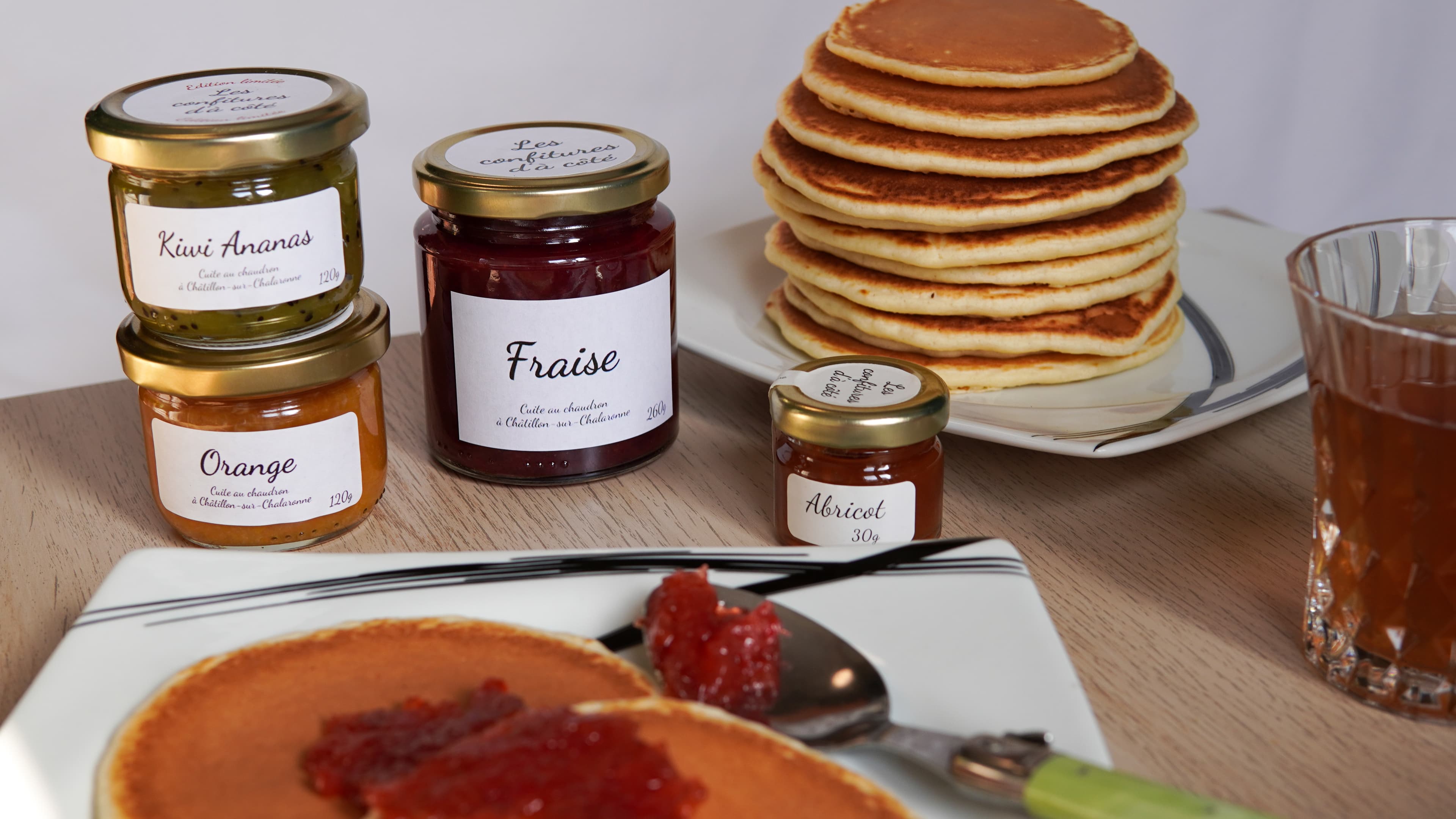 Petits pots de tartinades disposés sur une table de petit-déjeuner avec des pancakes